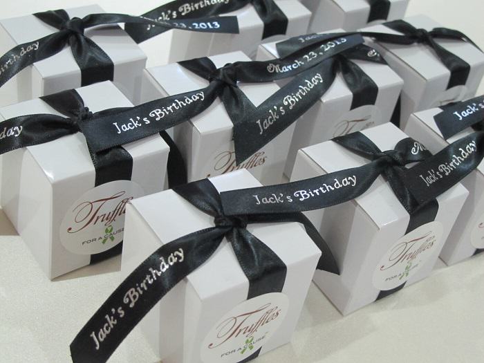Chocolate birthday favors displayed with black ribbons on a white box for Jack's birthday.